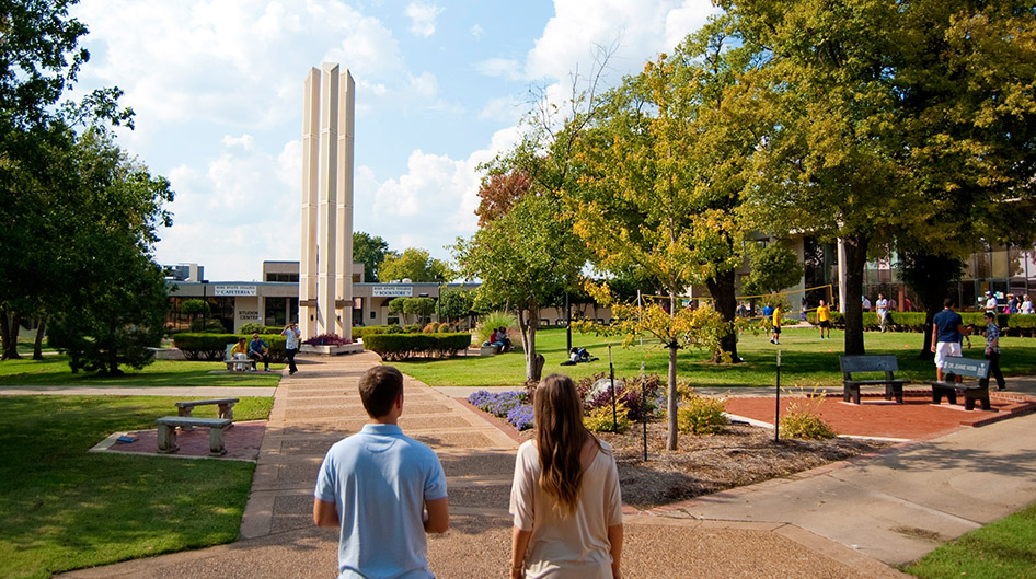 View of the central campus mall, two students, and the logo tower.
