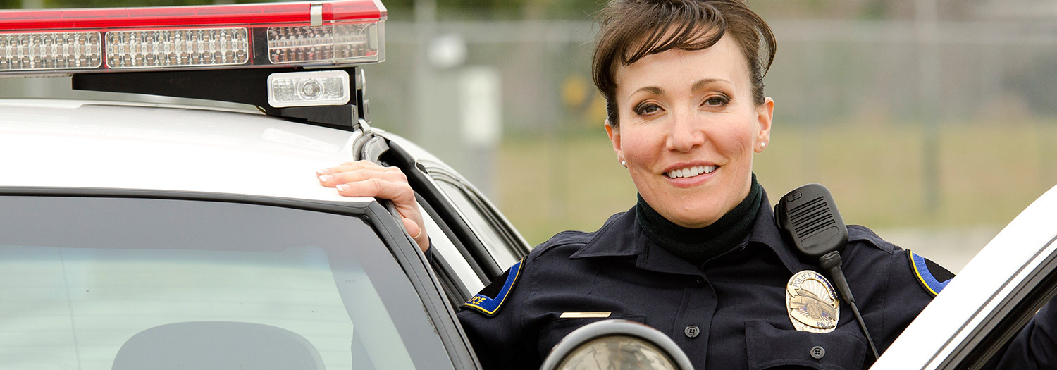 Smiling police officer standing at door of her car