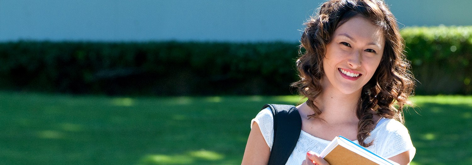 outdoor photo of a smiling female student holding books