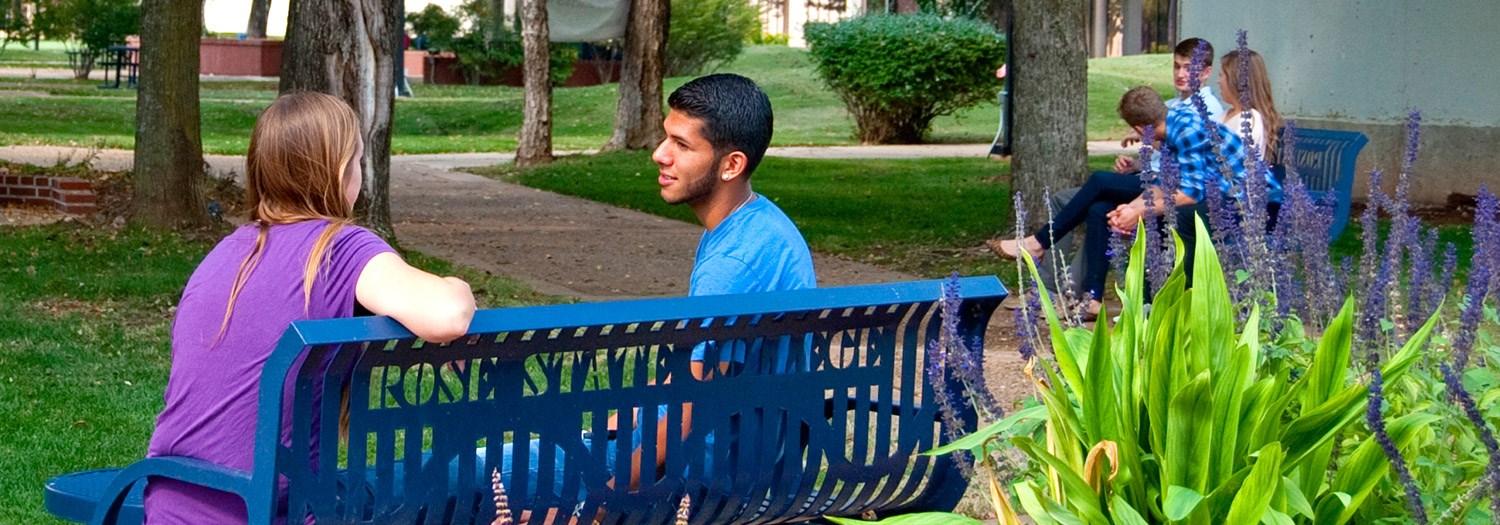 Students seated on a bench in the mall area.