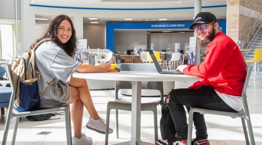 Two students sitting in the union smiling and studying.