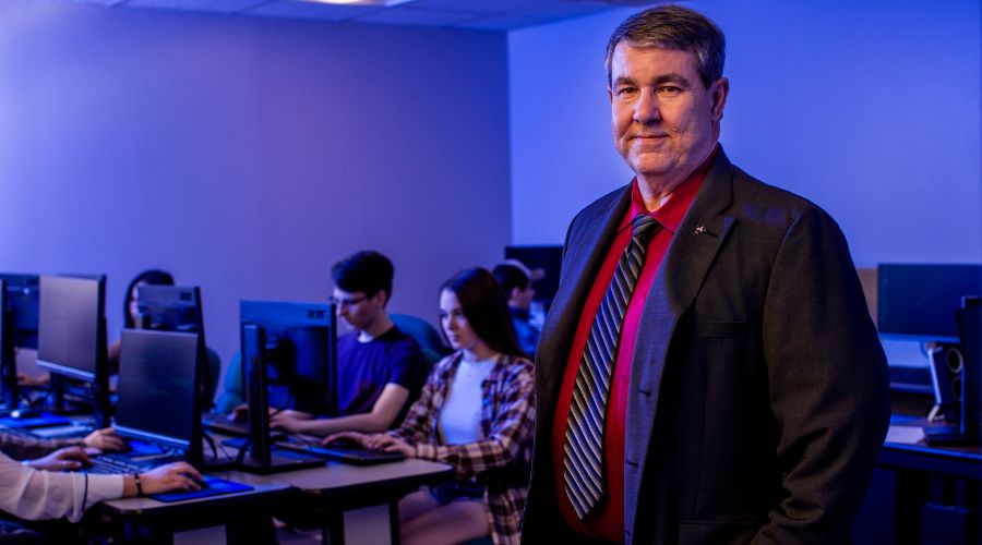 Ken Dewey poses for a picture in front of Cybersecurity students.