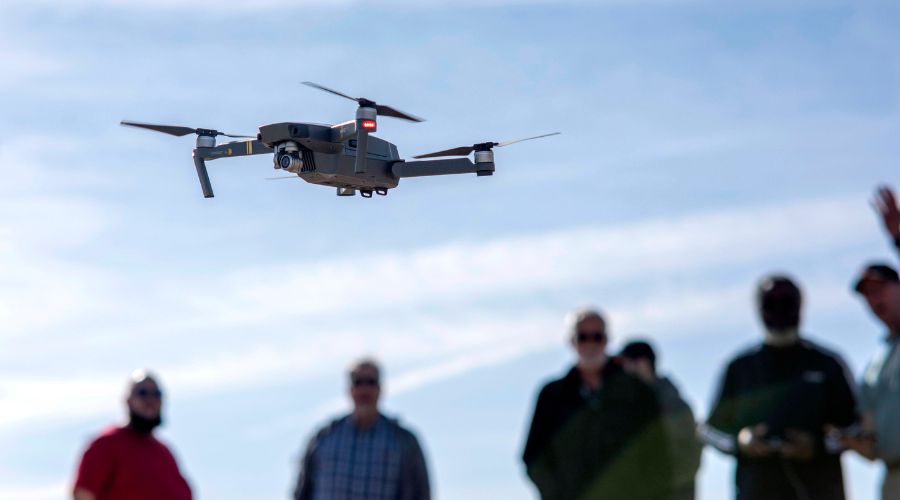 A drone flying mid air with a class of people in the background