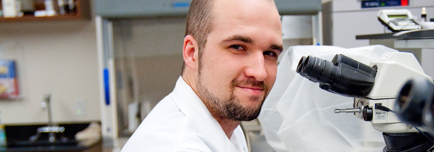 man sitting in front of a microscope