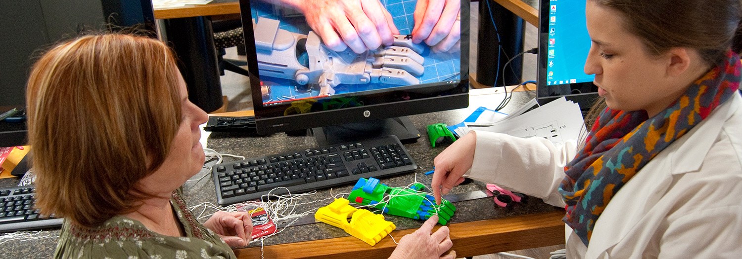 Two people working on mechanical hand