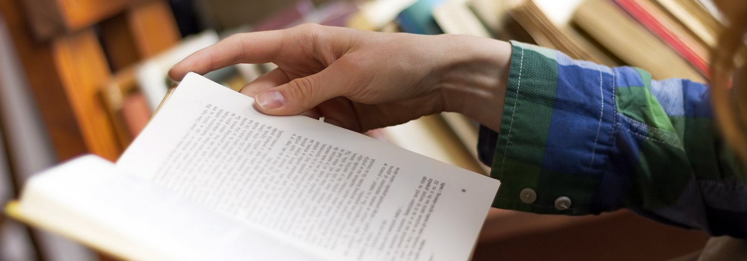 close up of a hand turning pages of a book
