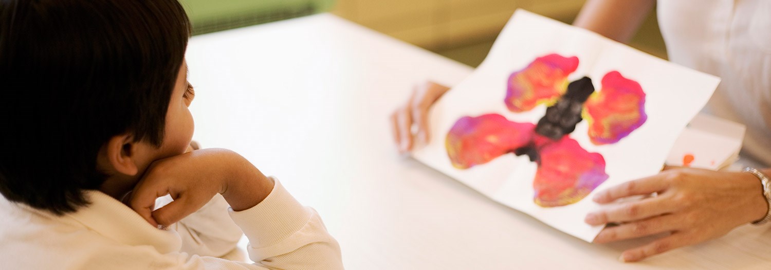 young male student looking at ink blots on cards