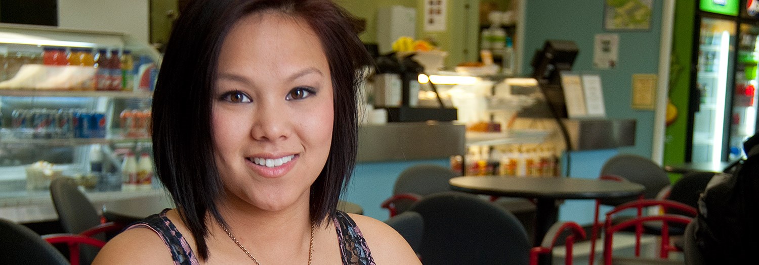 female standing in the cafeteria smiling 