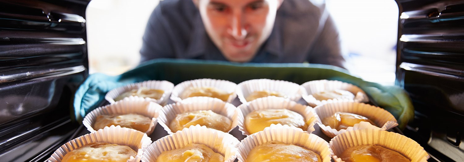 person taking baked goods out of an oven